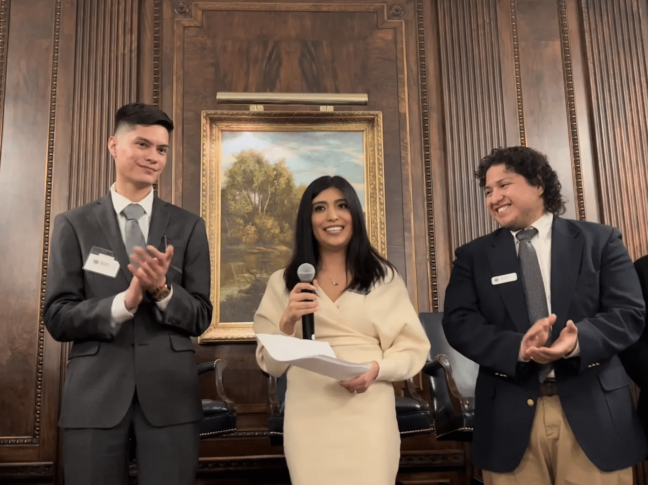 a group of people standing next to a person in a suit and tie a group of people standing next to a person in a suit and tie