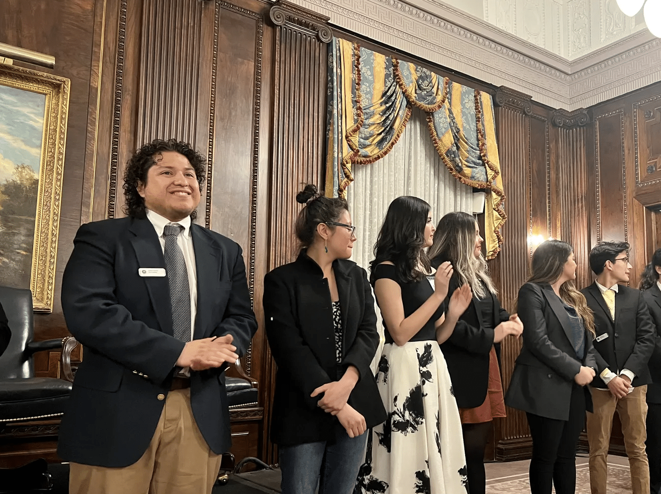 a group of people standing next to a person in a suit and tie